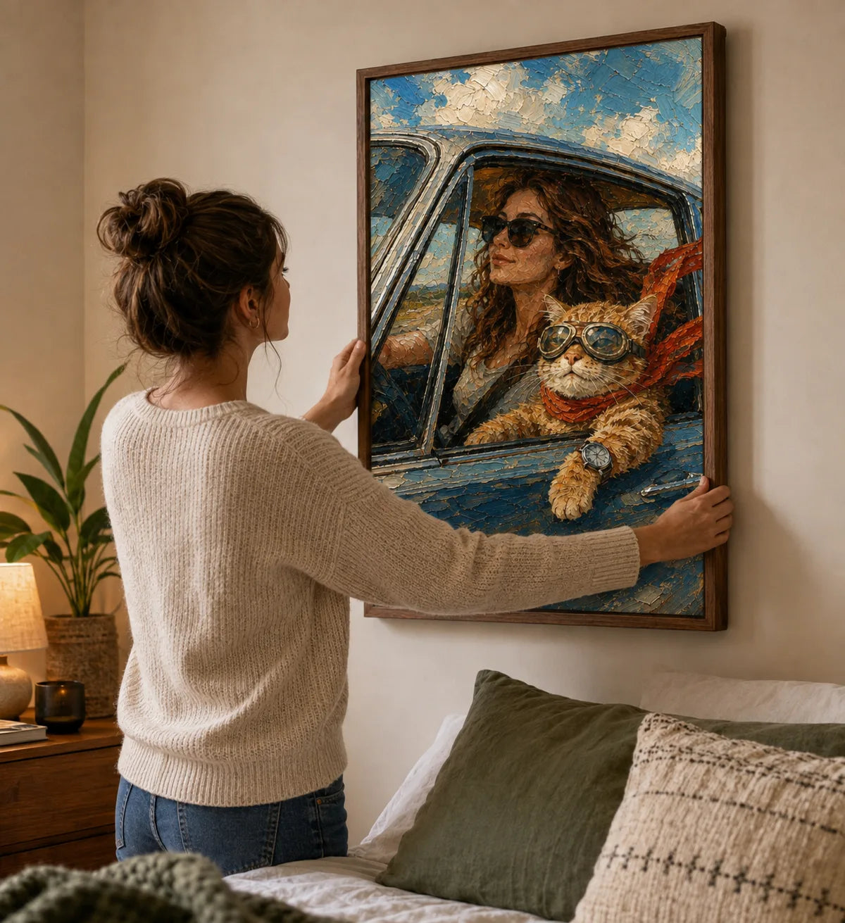 Pet parent hanging a framed road-trip portrait with her cat